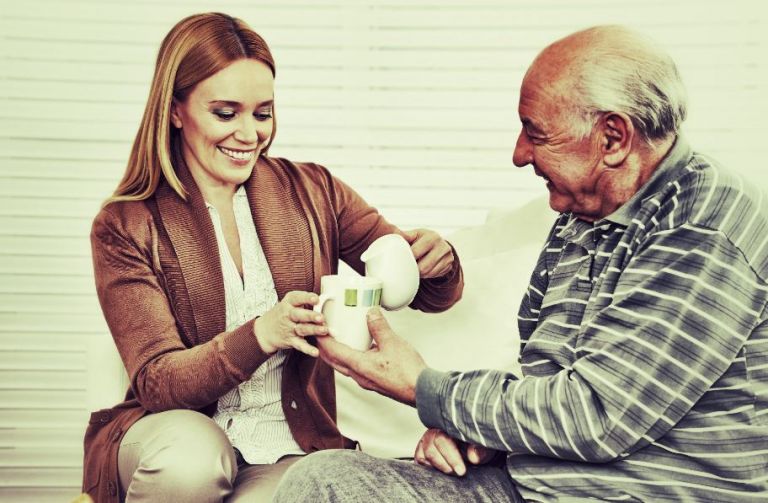 femme sert un verre de lait à un seniorpour calcium