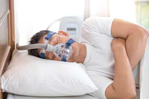 Homme dormant au lit portant un masque, contre apnée du sommeil