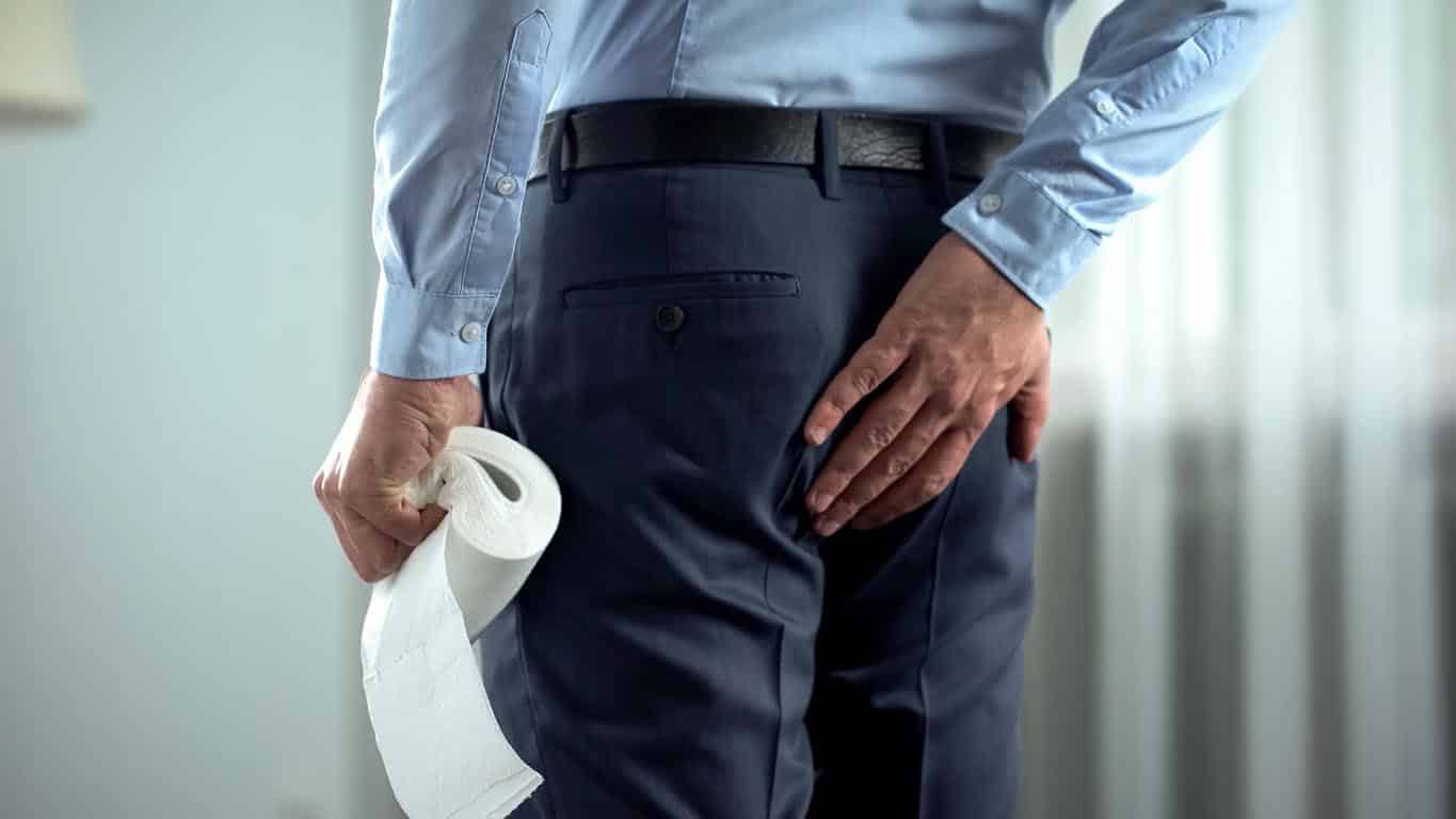 Employé de bureau avec du papier de toilette dans la main souffre de douleurs d’hémorroïdes