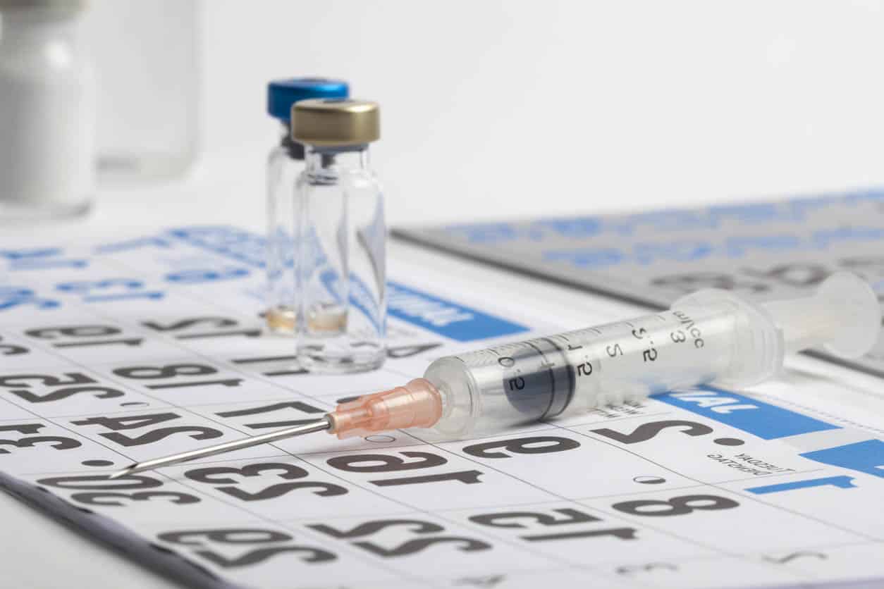 Seringue et plusieurs flacons vaccin sur un calendrier