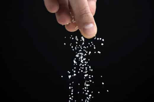 Hands Spreading Salt On Black Background