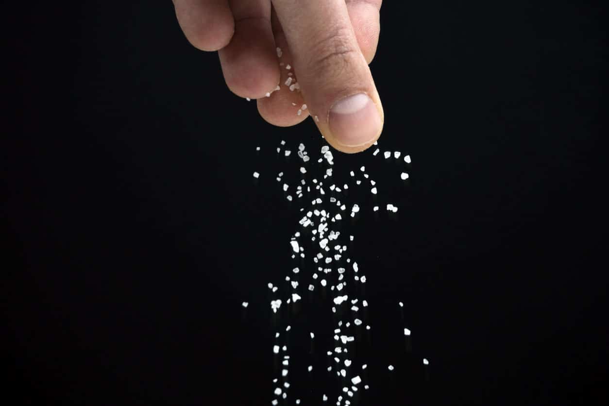 Hands Spreading Salt On Black Background