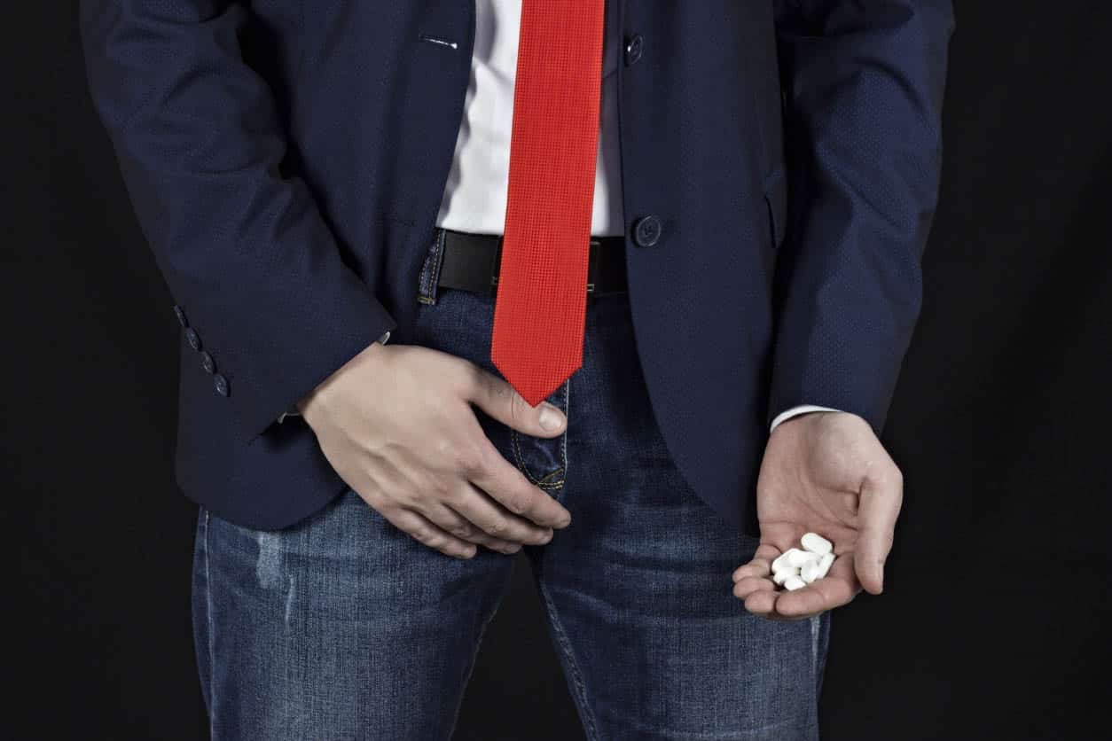 Businessman Holds A Groin, A Handful Of Pills In Her Hand