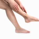 femmes touchant ses jambes lourdes