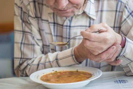 homme âgé avec la maladie de Parkinson retient la cuillère dans les deux mains