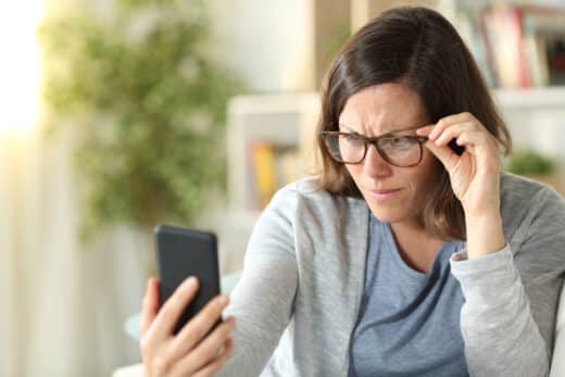 emme adulte avec des problèmes de vue lisant le téléphone à la maiso