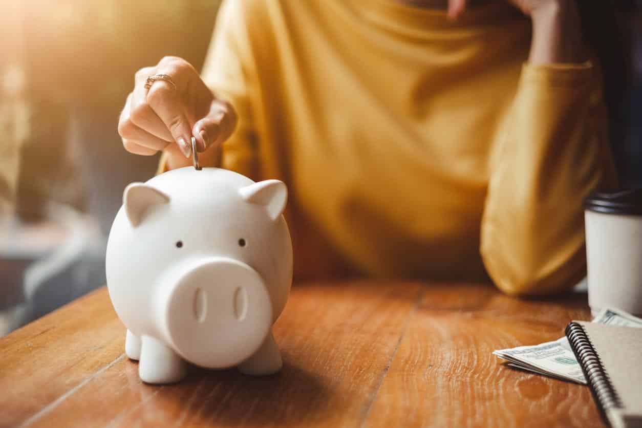 Woman Hand Putting Money Coin Into Piggy For Saving Money Wealth And Financial Concept.