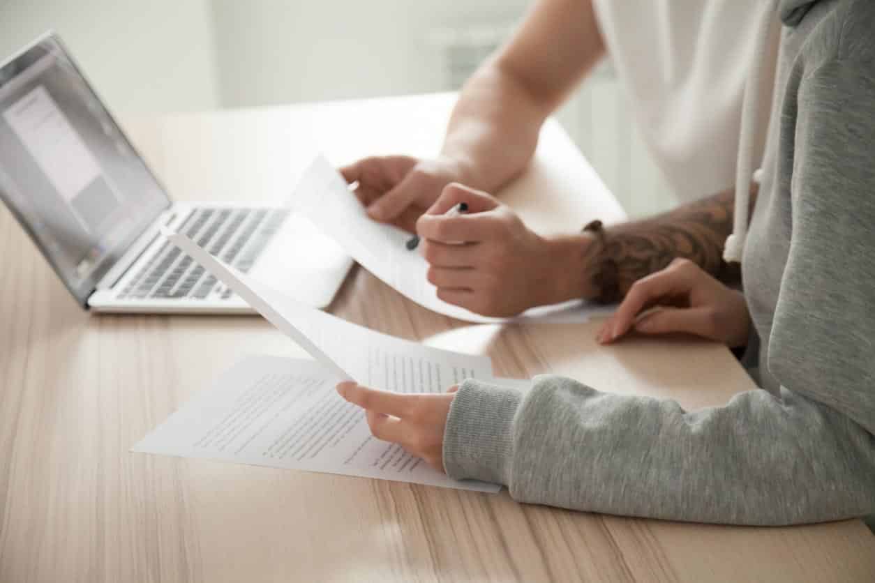 Couple Holding Reading Documents At Home With Laptop, Close Up