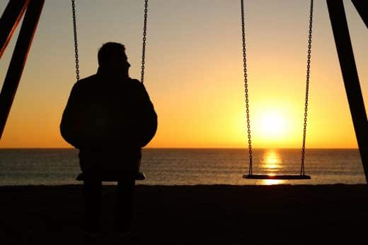 Man Alone On A Swing Looking At Empty Seat