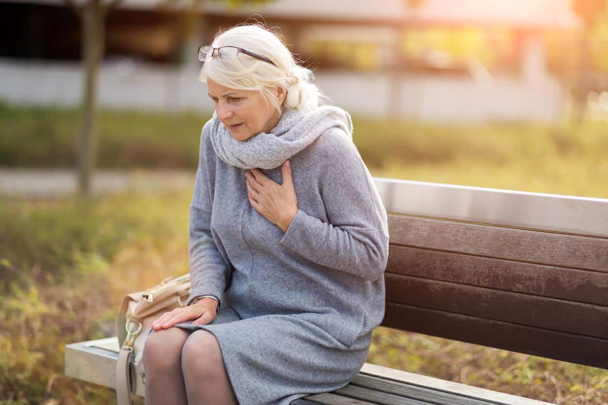 femme senior souffrant de douleurs à la poitrine tout en étant assis sur le banc