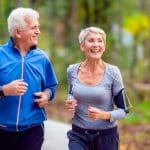 Couple de personnes âgées jogging dans le parc de sourire