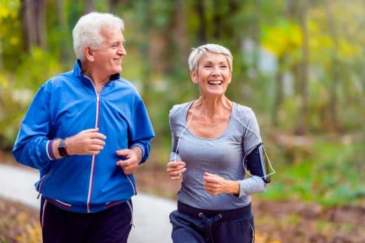 Couple de personnes âgées jogging dans le parc de sourire