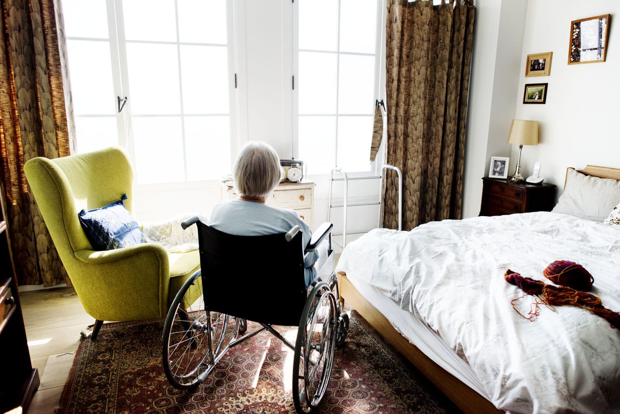 vieille femme assise dans un fauteuil roulant dans sa chambre