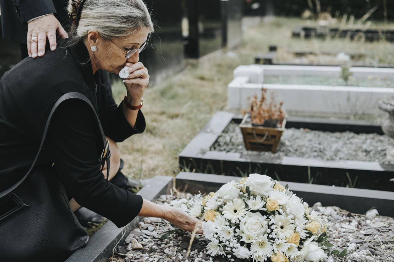 Old Woman Laying Flowers On A Grave