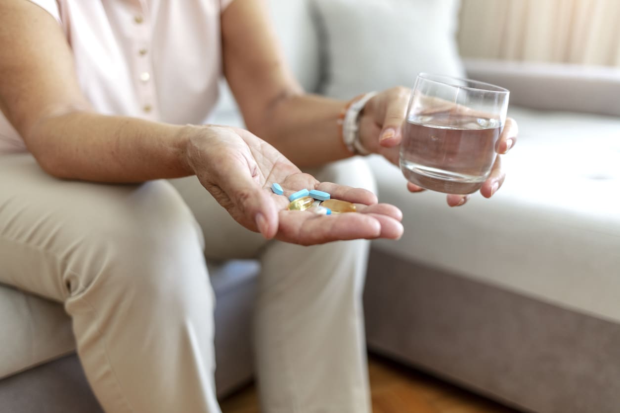 Une femme âgée prend des médicaments avec un verre d’eau contre la sinusite