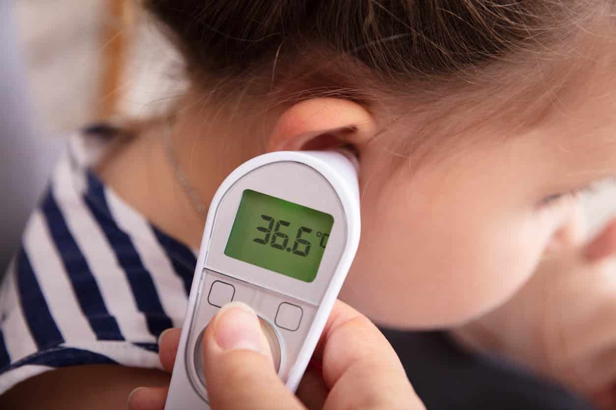 Main vérifiant l'oreille de la jeune fille avec thermomètre numérique auriculaire 