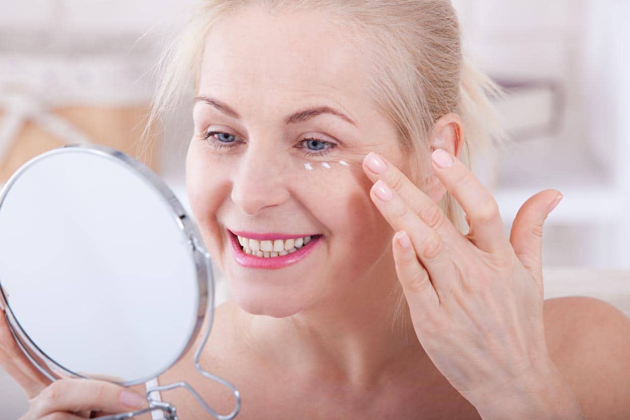 Femme âgé moyen regardant des rides dans le miroir