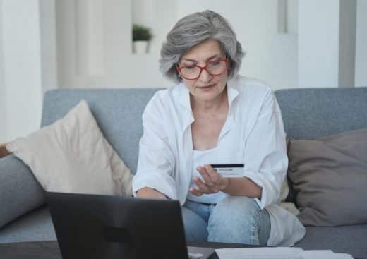 femme senior effectuant un don avec sa carte de credit sur internet