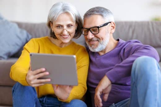 couple mature portant des lunettes regardant une tablette avec le sourire