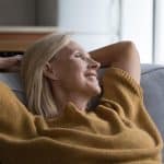 Gros plan femme âgée paisible se relaxant appuyée sur un canapé