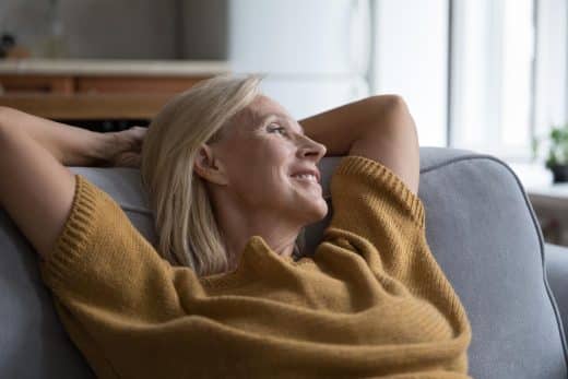 Gros plan femme âgée paisible se relaxant appuyée sur un canapé