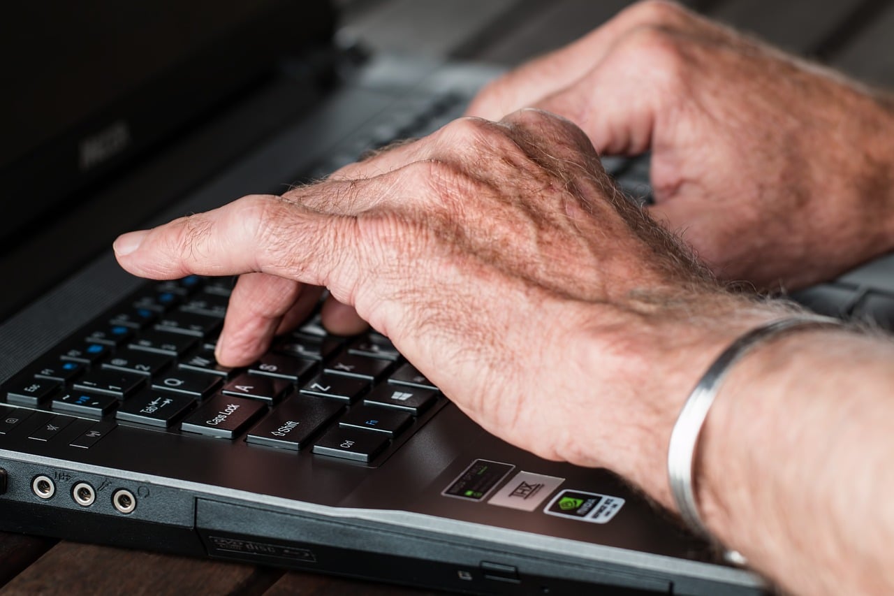 homme senior qui ecrit sur un clavier
